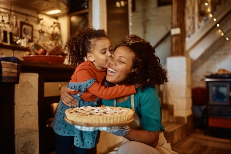 daughter kissing mother on the cheek after baking pie